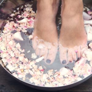 Voeten in voetbadje met rozenblaadjes