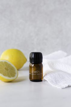 opengesneden citroen, flesje essentiële olie lemon en witte handdoek