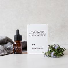 witte verpakking Rosemary, flesje essentiële olie Rosemary, takje rozemarijn en grijze handdoek